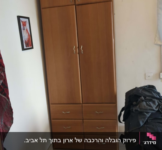 ארון עץ עם מגירות ותיק שחור על כיסא